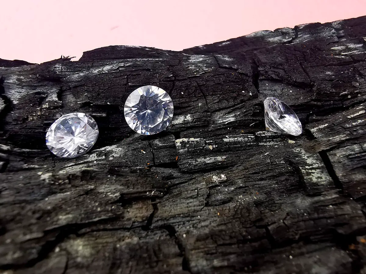 Close-up of three diamonds resting on rustic charcoal