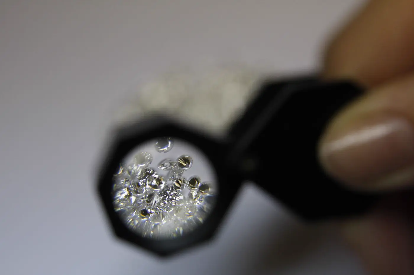 Close-up from above of a jeweller with a magnifying glass and diamonds